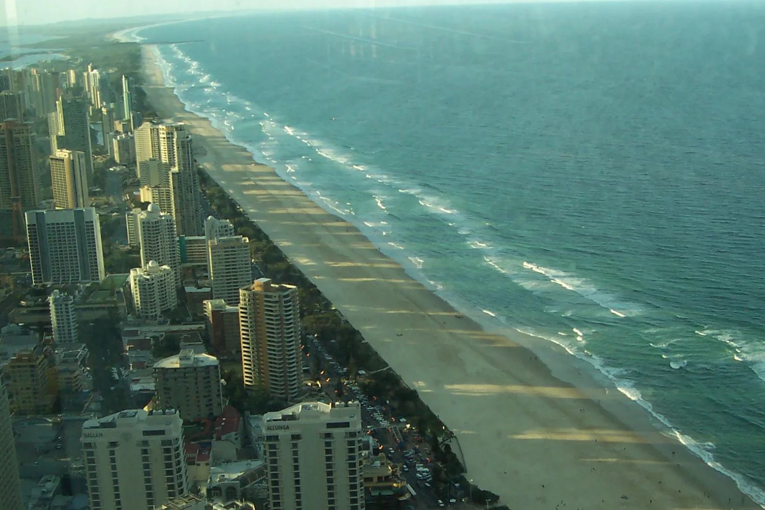 Looking down from high above Surfers Paradise: a line of towers along the beach, their shadows falling across the sand