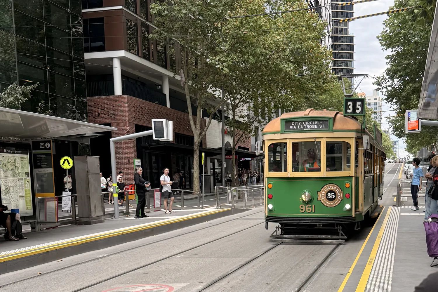 A green-and-cream City Circle heritage tram at a stop in the Melbourne CBD