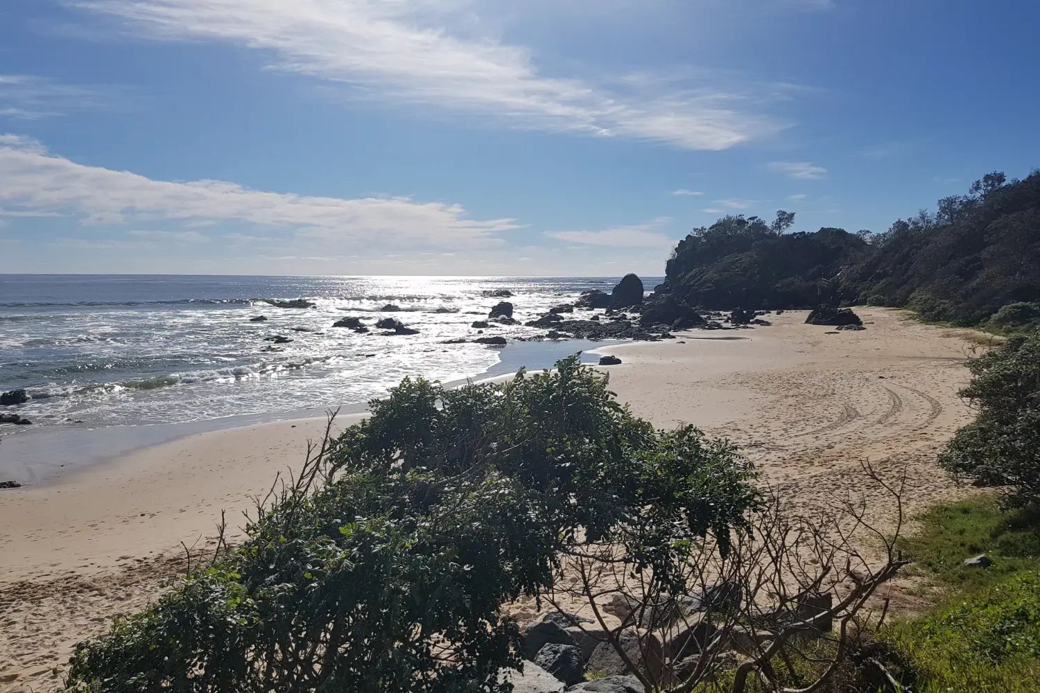 Flynns Beach at Port Macquarie: pale sand between dark rocks, with low headlands and the sea beyond