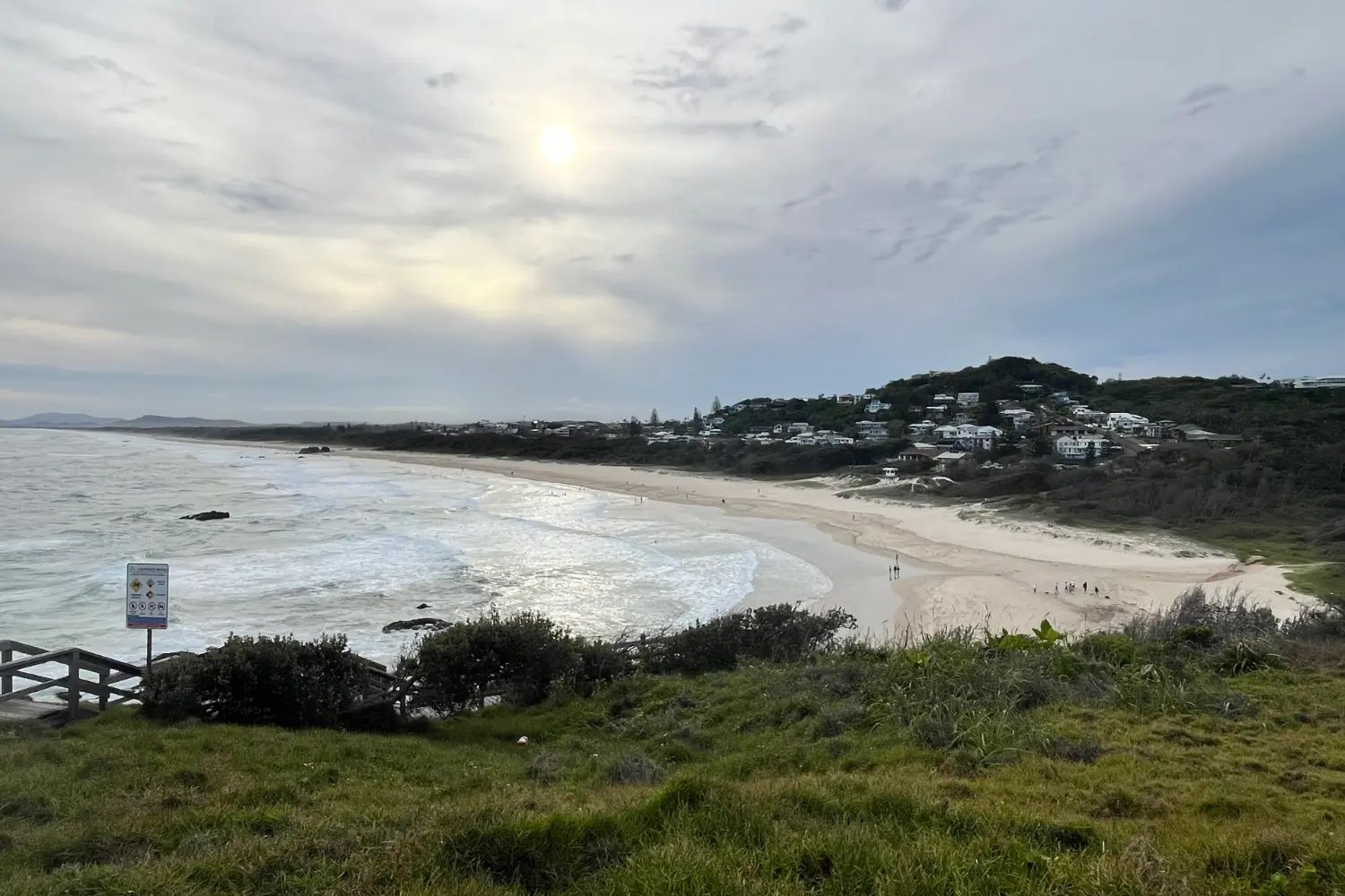 Lighthouse Beach seen from Tacking Point, a long curve of sand running south with surf breaking along it