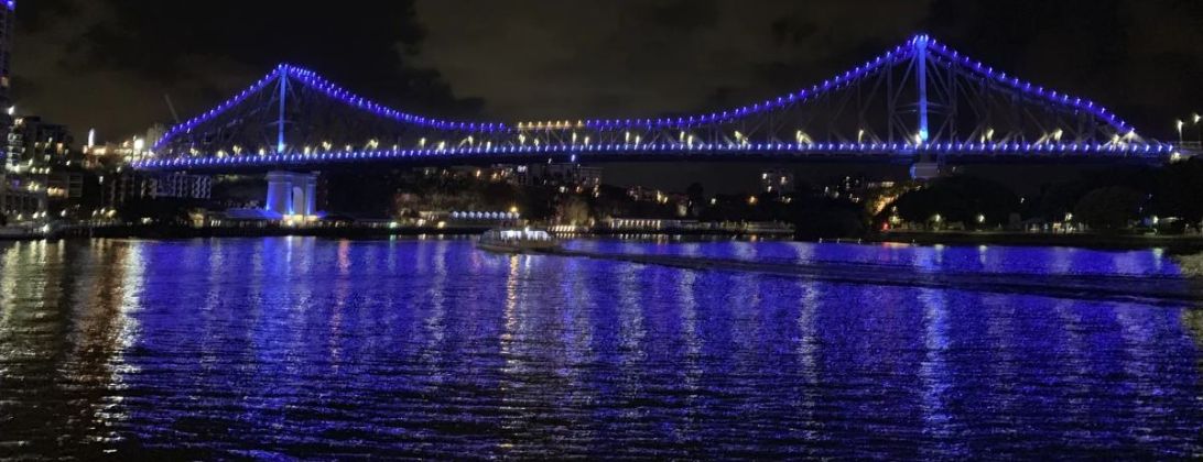 The Story Bridge in Brisbane lit blue at night, reflected in the river