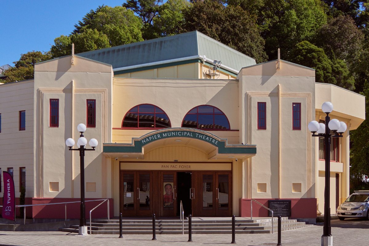 The cream facade of the Municipal Theatre in Napier, with arched windows over the entrance and globe lamp posts in front