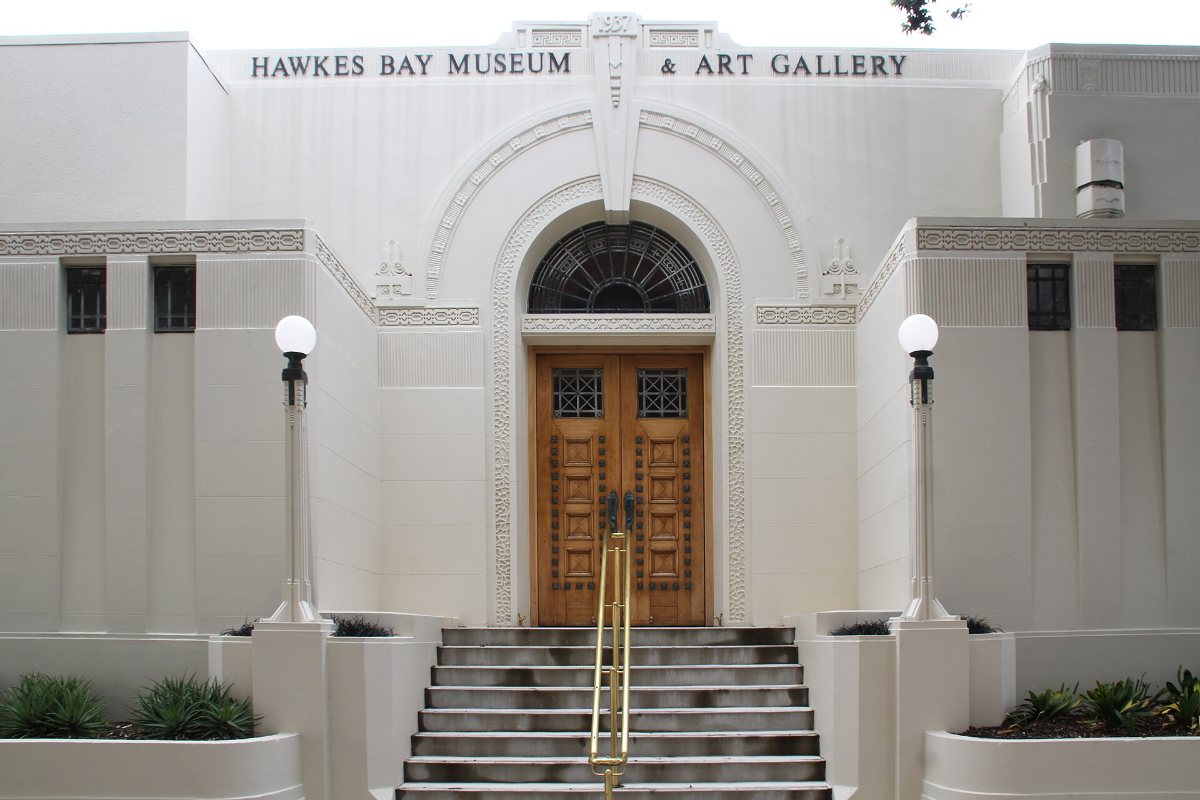 The white Art Deco entrance of the Hawke&rsquo;s Bay Museum and Art Gallery in Napier, with steps up to a wooden door.