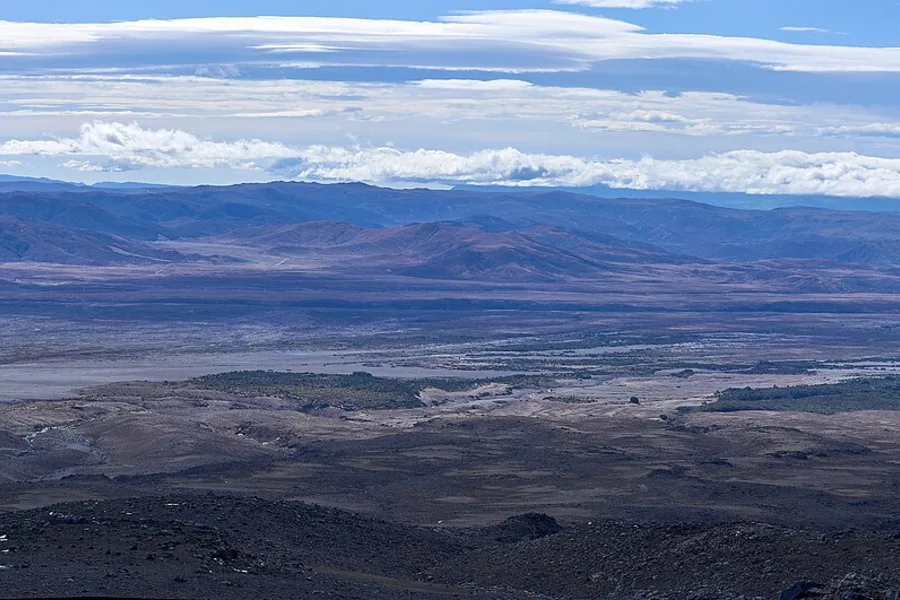 The Rangipo Desert seen from the slopes above, a wide brown volcanic plain under a band of cloud.