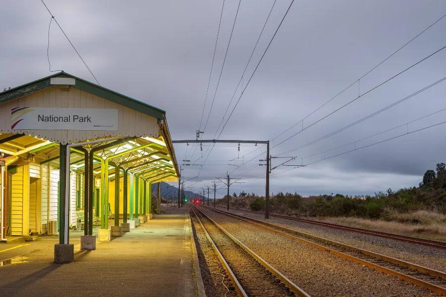 The yellow and green platform building at National Park railway station, with the Main Trunk line running into the distance.