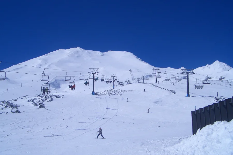 Chairlifts climbing the broad white slopes of Tūroa on Mount Ruapehu under a deep blue sky.