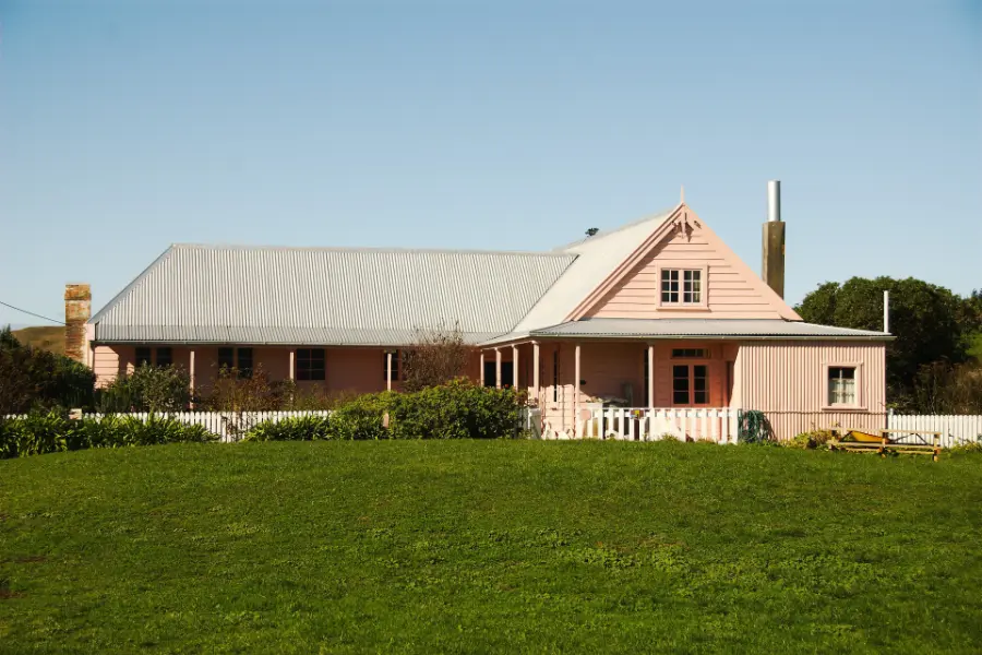 Fyffe House, a pink-painted cottage with a corrugated-iron roof, set behind a lawn and picket fence.