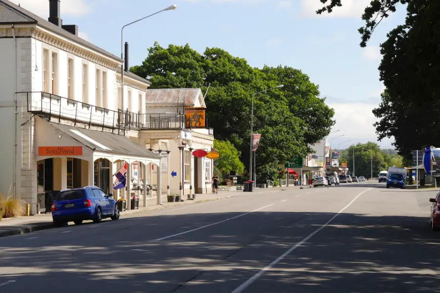 The wide main street of Fairlie, with low shopfronts and a two-storey heritage building under a blue sky.