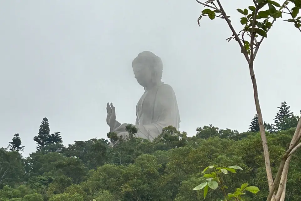 The Tian Tan Buddha in mist above the trees of Ngong Ping